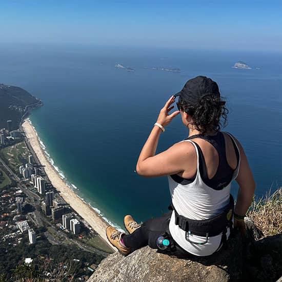 Lydiana em cima de um monte olhando para a praia